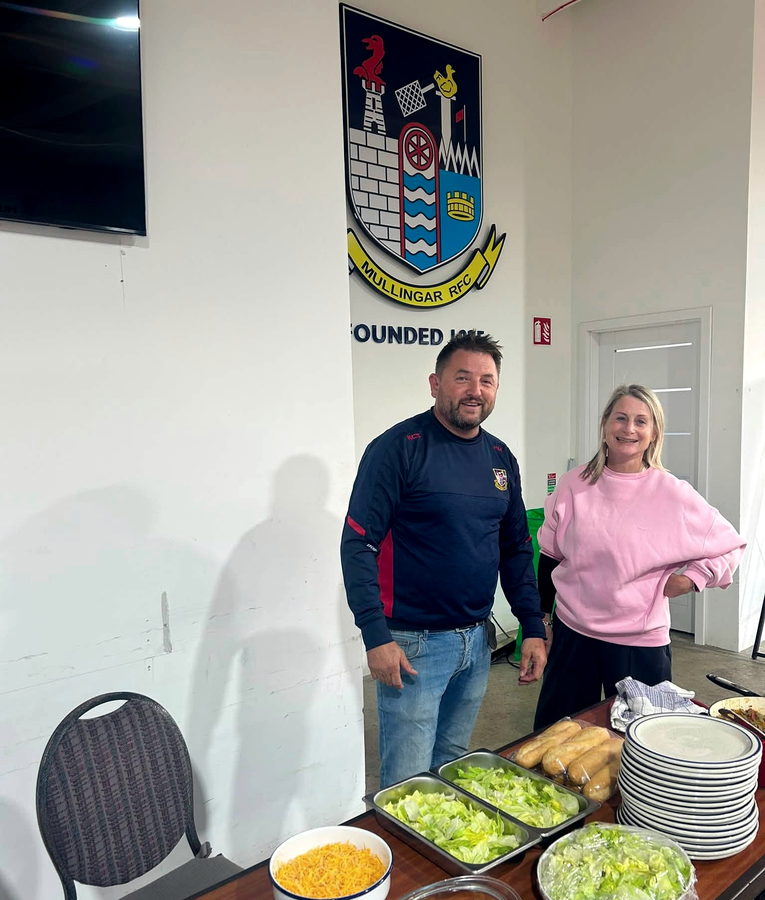 The Mullingar RFC crest on the clubhouse wall above a table set for a club function.
