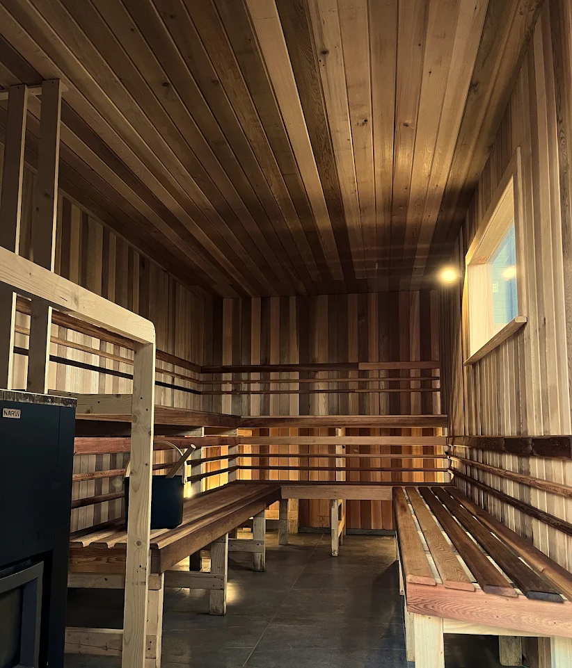 Inside the sauna: tiered cedar benches, a stove and a small window